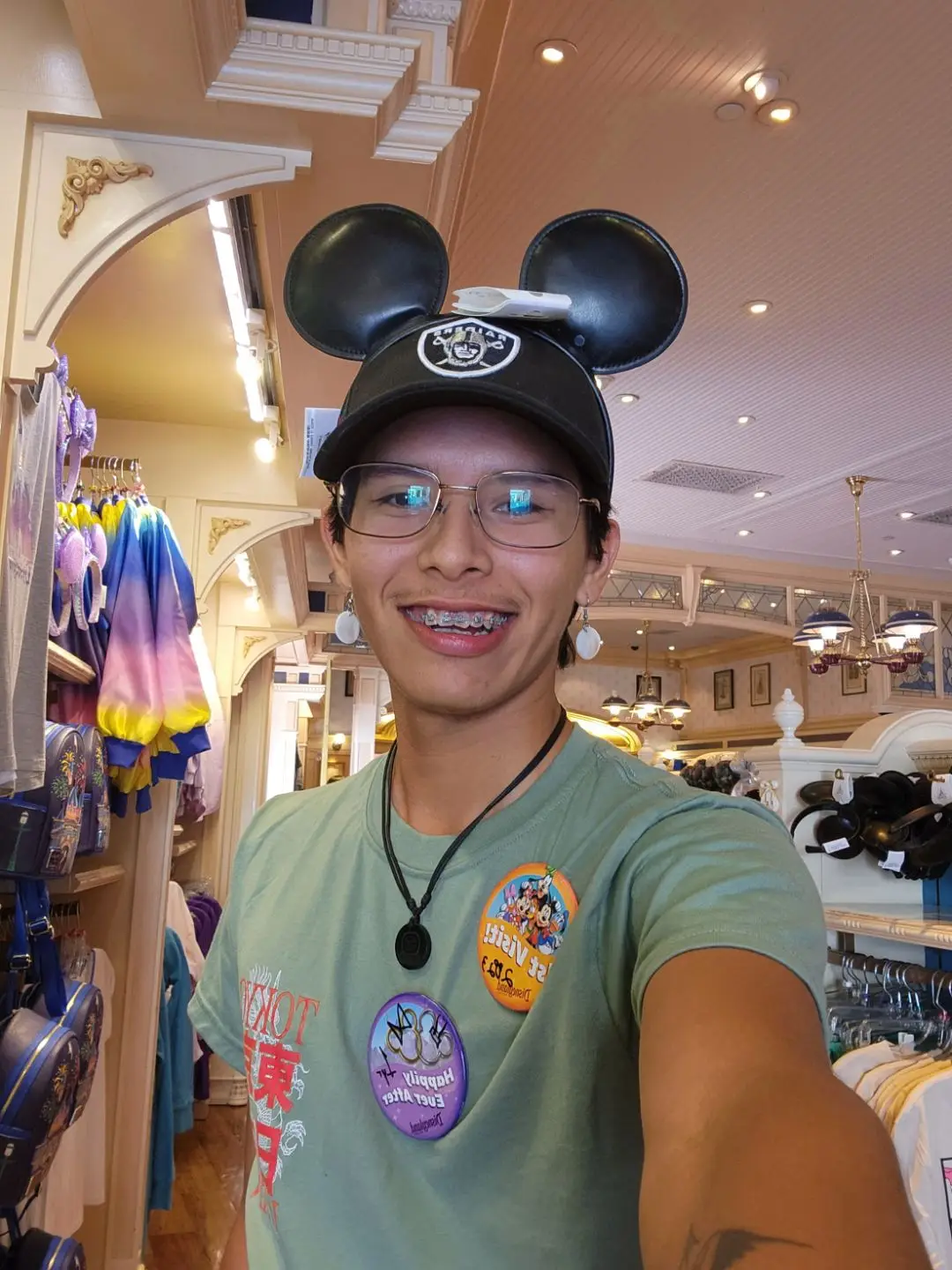 Smiling theme park team member wearing Mickey Mouse ears and glasses inside a gift shop.